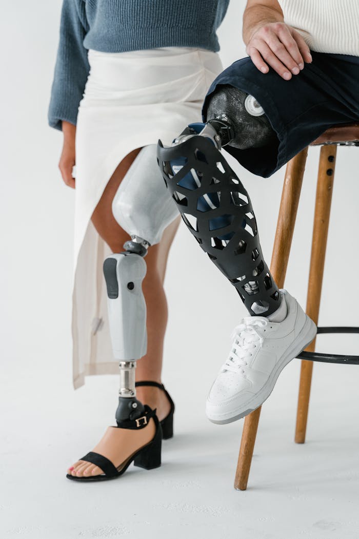 Close-up of prosthetic legs on man and woman sitting in a studio.